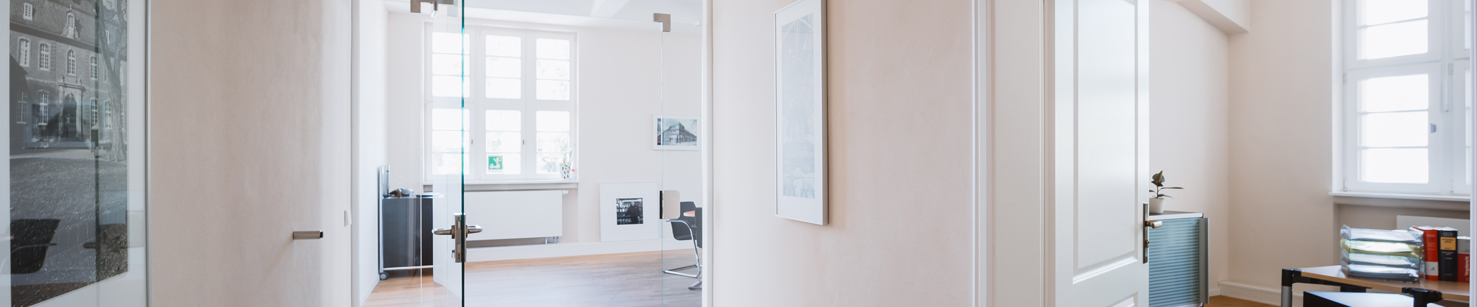 Innenansicht eines hellen Büros mit Glastüren und großen Fenstern.