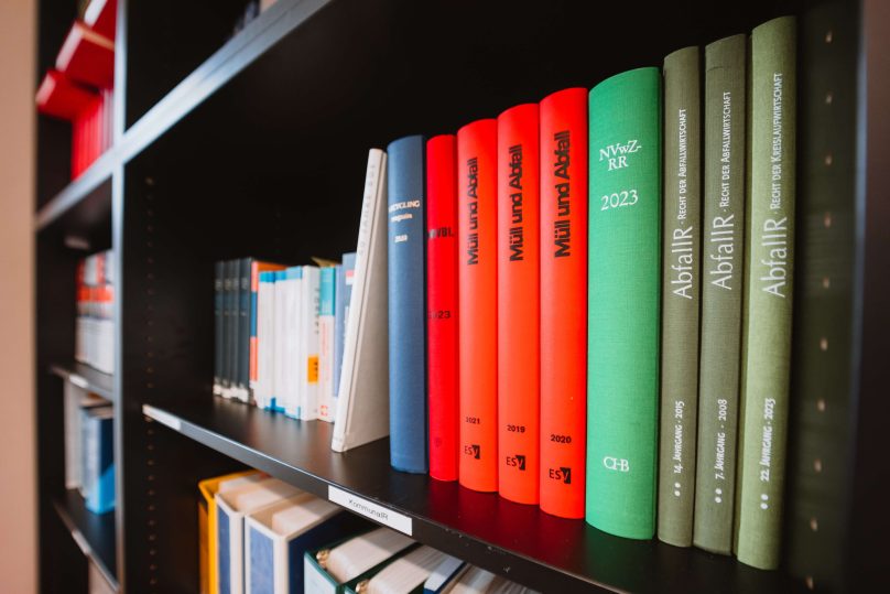 Bücherregal mit bunten Büchern zu den Themen Müll und Abfall.
