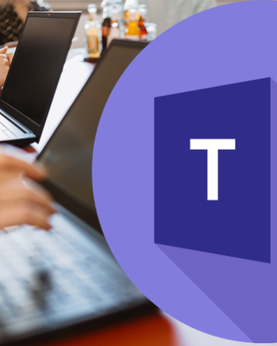 Personen arbeiten an Laptops an einem Tisch; daneben ist ein großes Microsoft-Teams-Logo