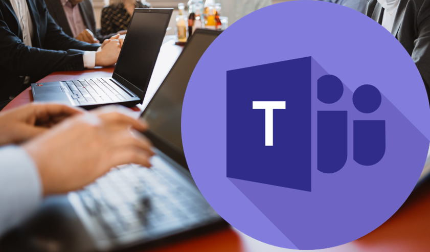 Personen arbeiten an Laptops an einem Tisch; daneben ist ein großes Microsoft-Teams-Logo